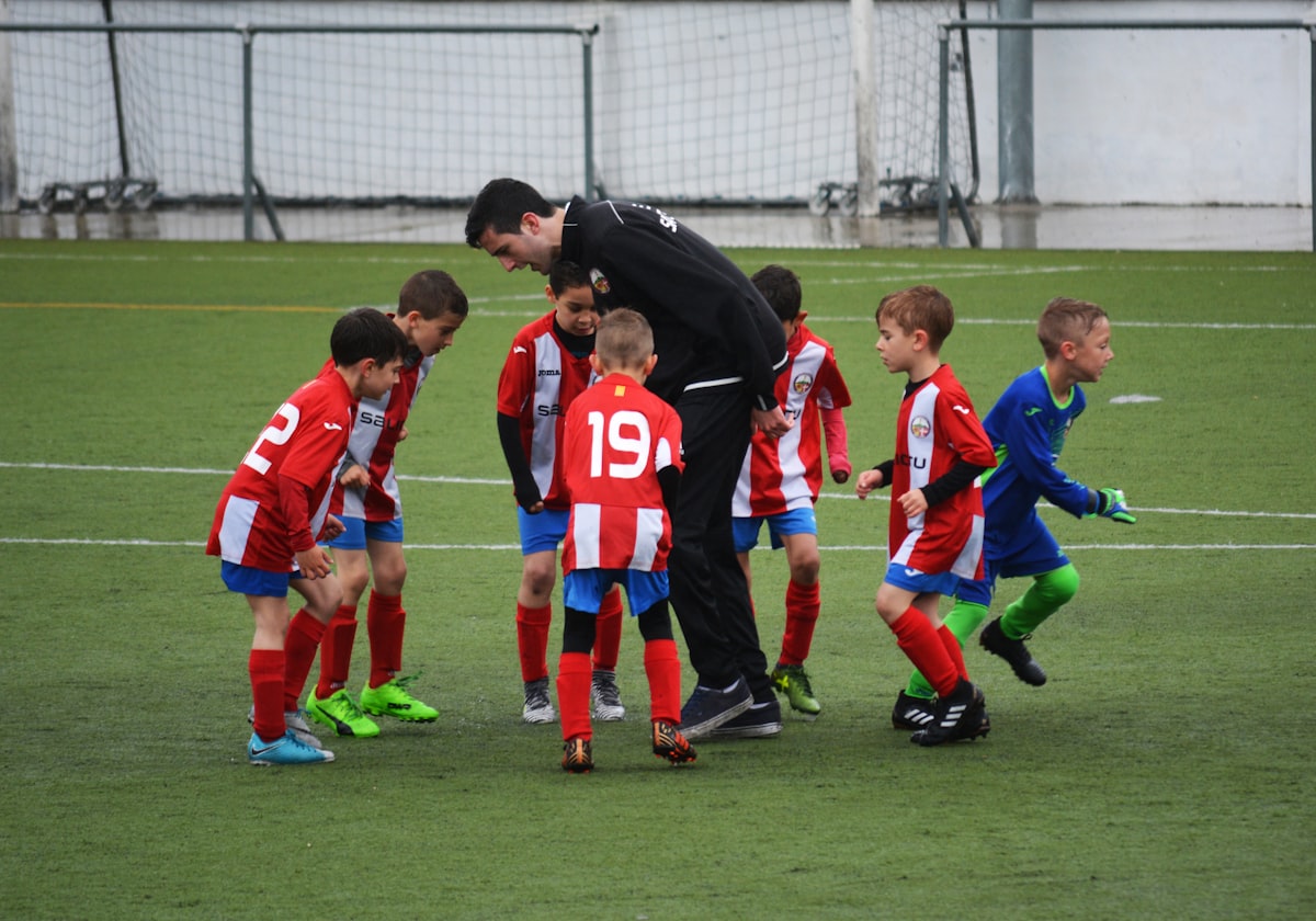 Trainer bespricht sich mit einer Kindermannschaft auf dem Platz